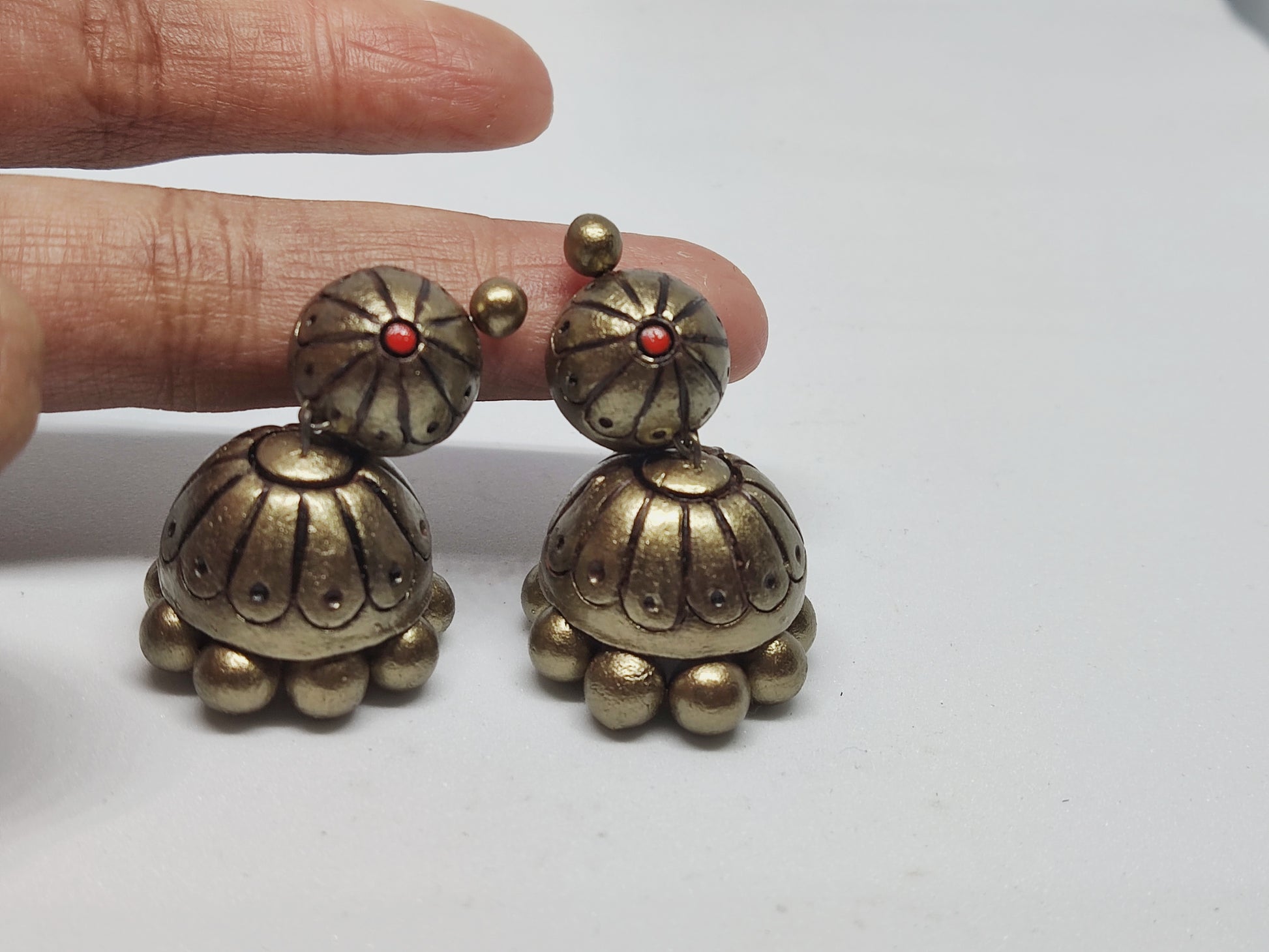 Buy Rachana Terracotta Jhumka online from Anusangi Collections with antique gold finish and red bead detail