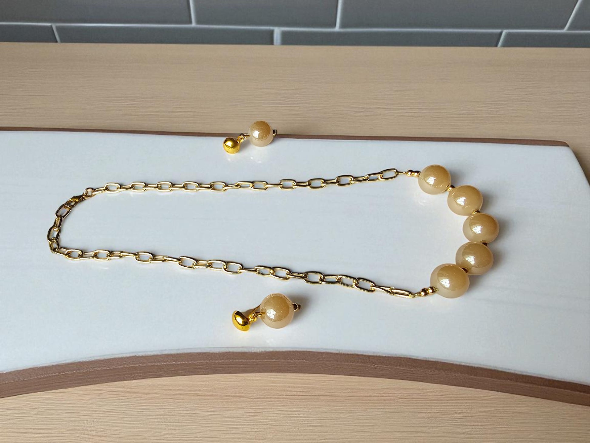 Anusangi Collections elegant glass pearl jewelry for women featuring a golden chain and soft-colored pearls