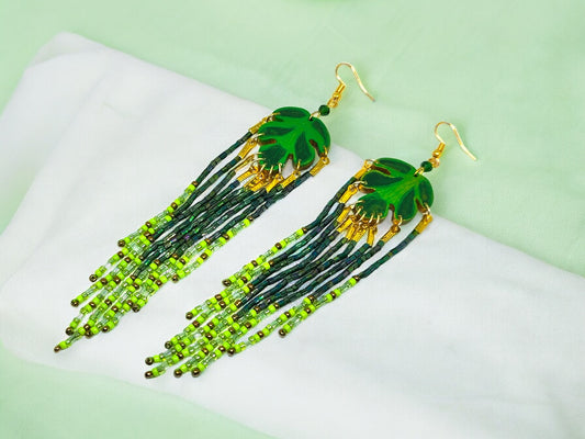 Anusangi Collections green leaf beaded earrings with dangling green and black beads on white fabric