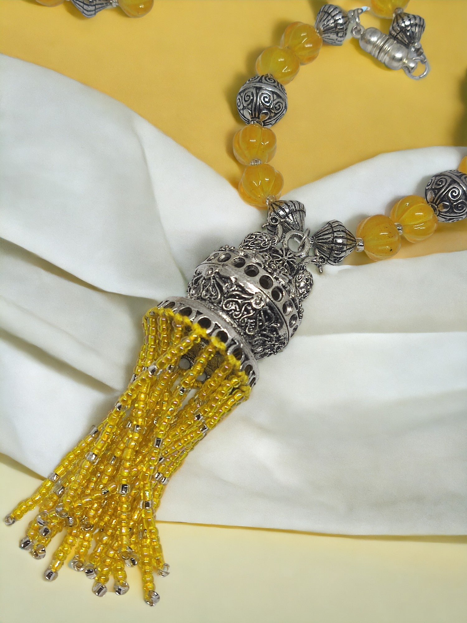 Anusangi Collections handmade beaded jewelry set featuring yellow beads and ornate silver pendant with tassels
