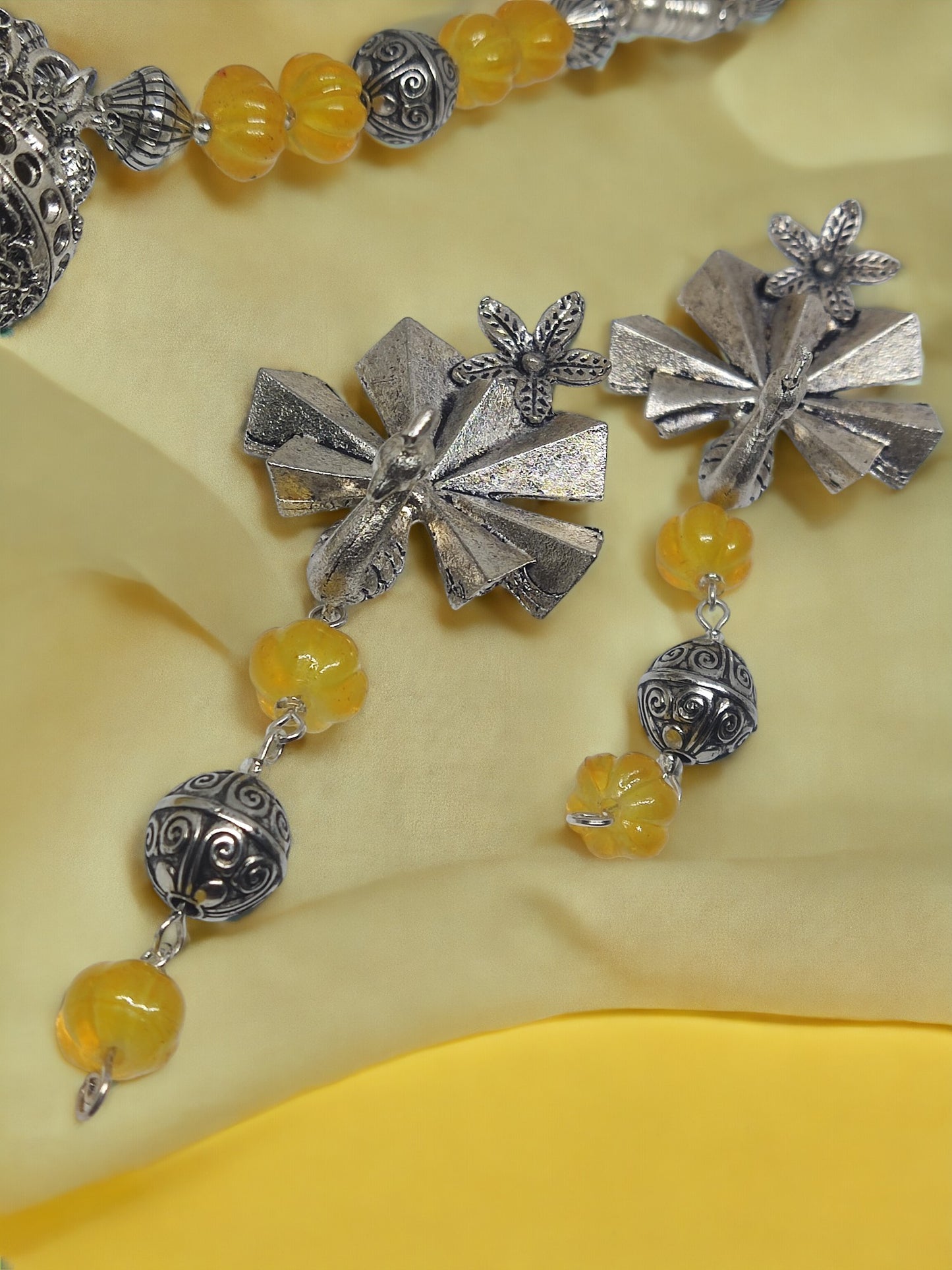 Anusangi Collections handmade beaded jewelry set featuring silver floral earrings with yellow and silver beads