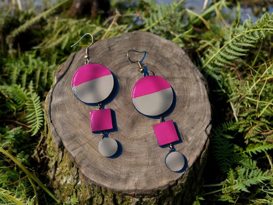 Anusangi Collections terracotta pink and gray statement earrings displayed on wood with greenery background
