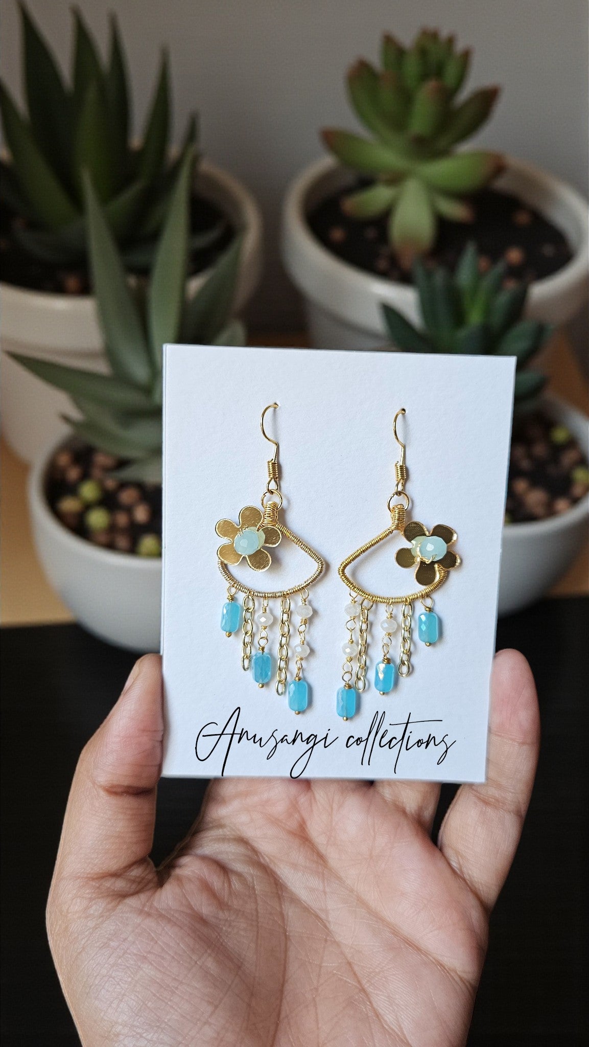 Sky Garden Dangles with floral designs and turquoise beads beaded earrings from Anusangi Collections held in hand