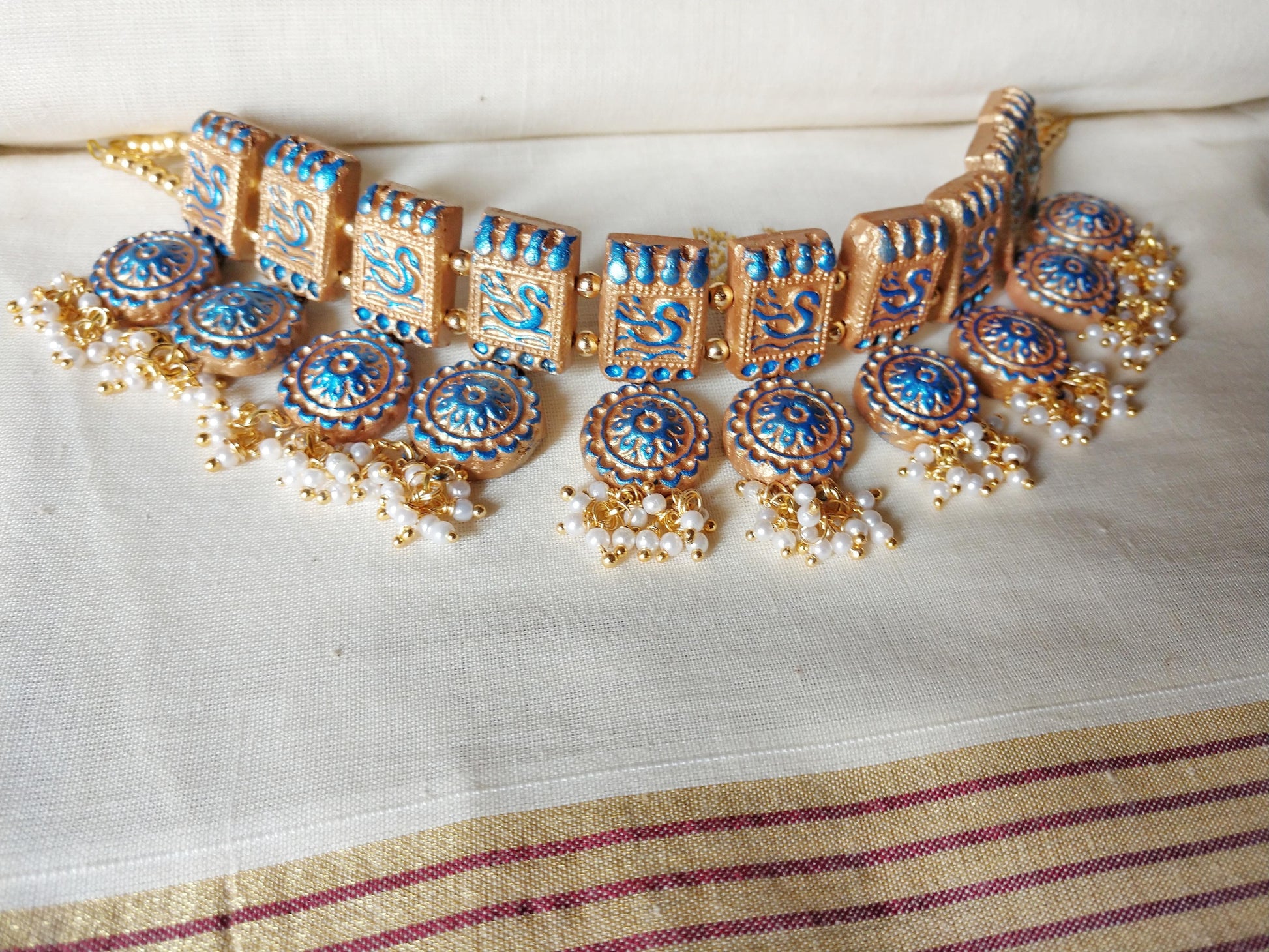 Anusangi Collections terracotta jewelry set featuring a traditional fabric choker necklace with blue and gold detailing
