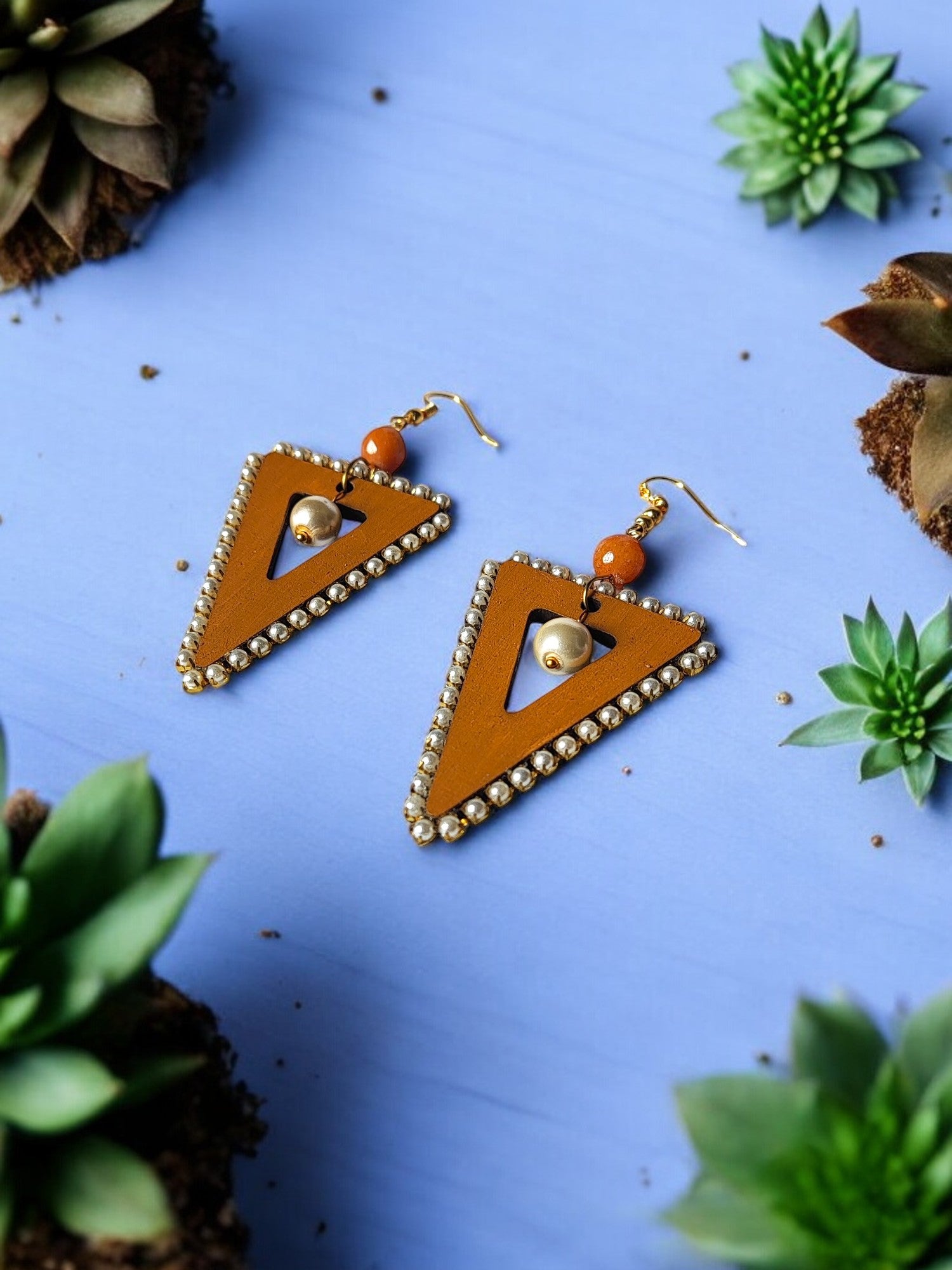 Anusangi Collections orange triangle statement earrings with beads and golden accents on blue background