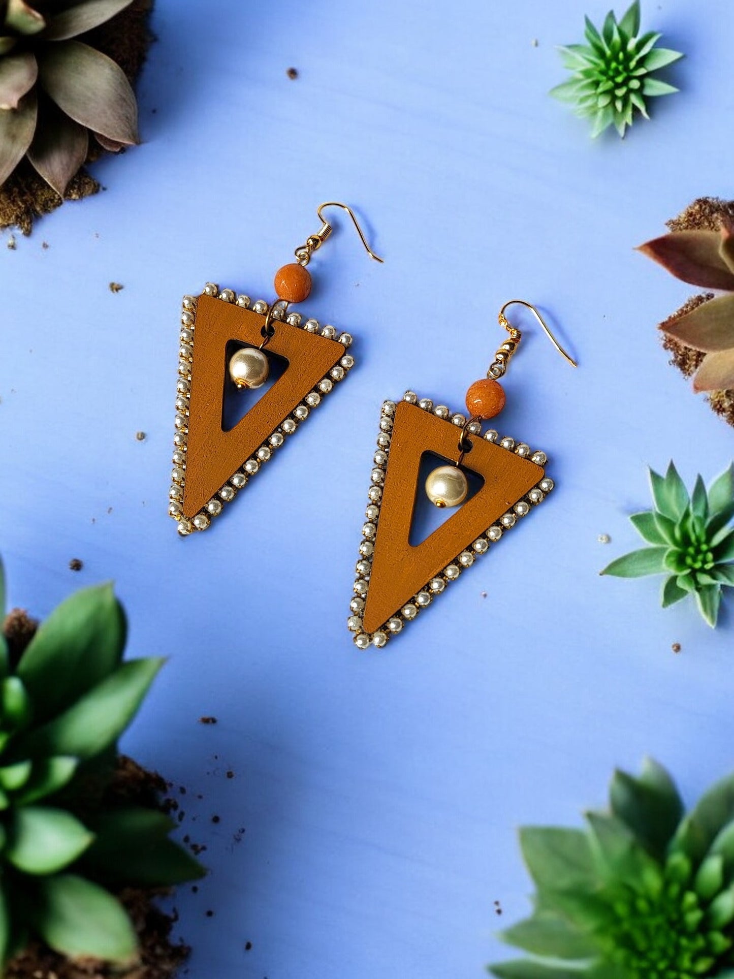 Anusangi Collections triangle statement earrings with brown beads and golden accents on a blue background