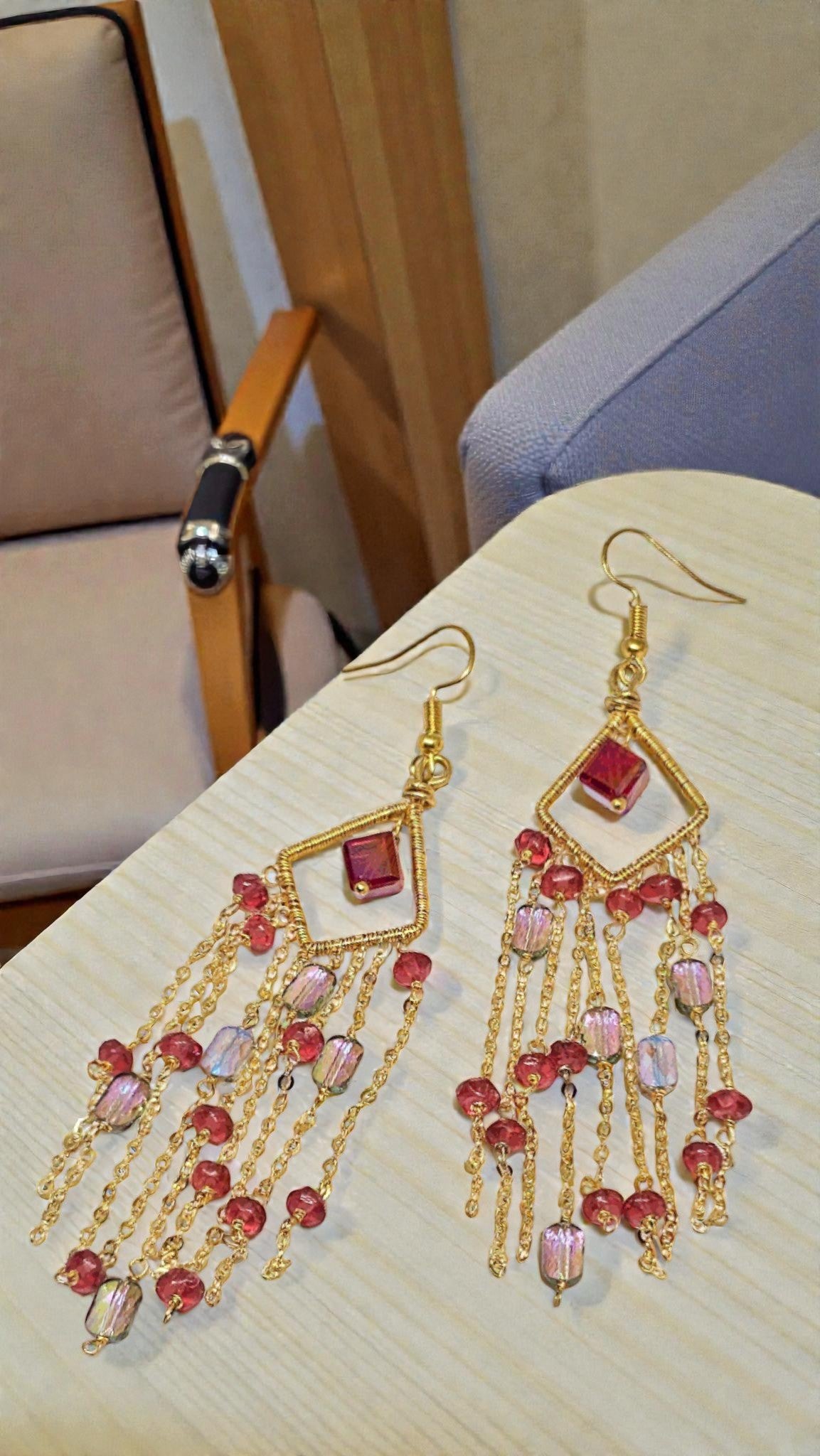 Rose Aurora Cascade Earrings by Anusangi Collections with gold chains and pink beads on beige table