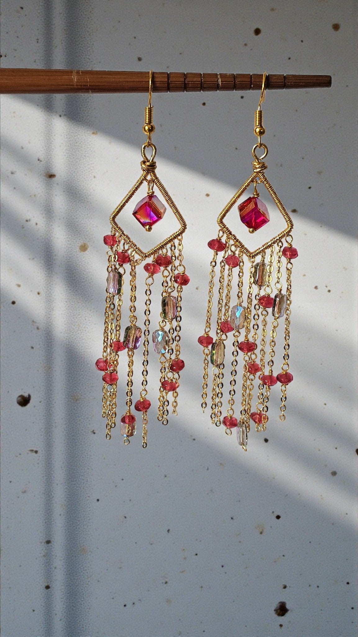Anusangi Collections Rose Aurora Cascade Earrings with pink beads and gold chain tassels hanging from geometric frames